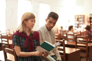 Kitaplığındaki kitap okuyan ile öğrenciler