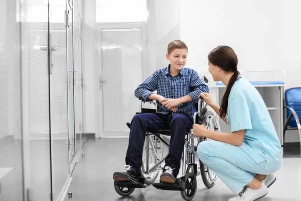 年轻女医生照顾在轮椅的人在室内 — 图库照片