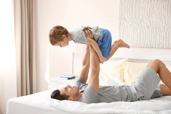 Happy family lying under blanket in bed at home