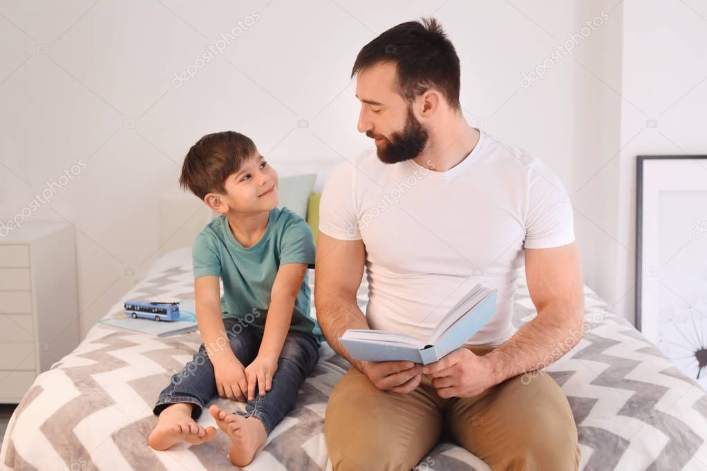 Father reading book to his little son at home