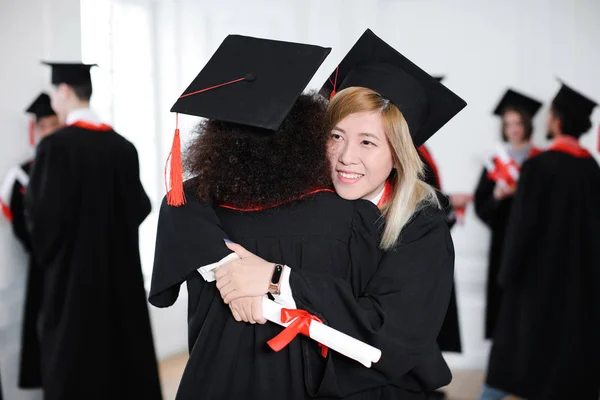 Щасливі Студенти Холостяцькому Одязі Обіймаються Приміщенні День Випуску — стокове фото
