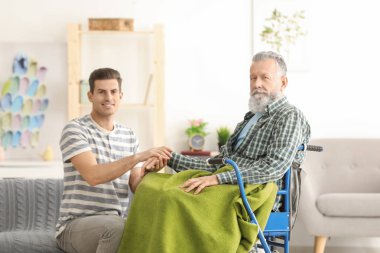 Young caregiver with senior man at home clipart