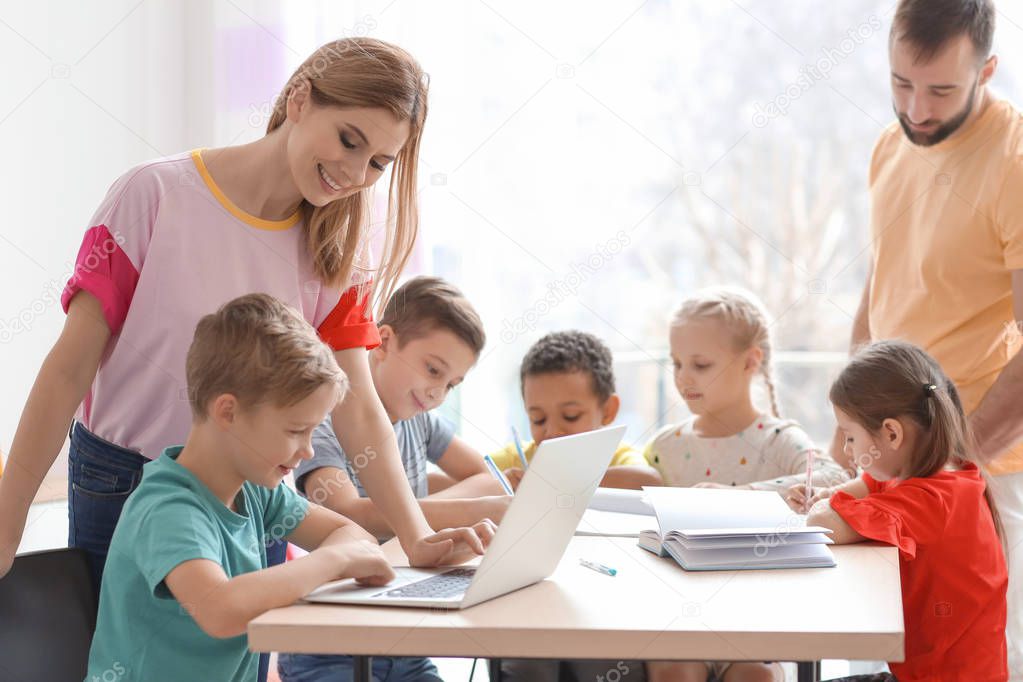 Teachers helping children with homework in classroom at school