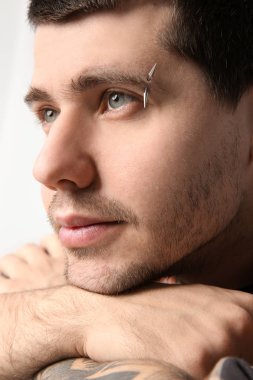 Young man with pierced eyebrow on light background, closeup clipart