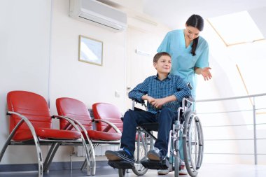 Genç kadın doktor kapalı tekerlekli sandalyede küçük çocuk bakımı