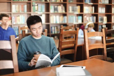 Kitaplığındaki kitap okuyan ile Asya öğrenci