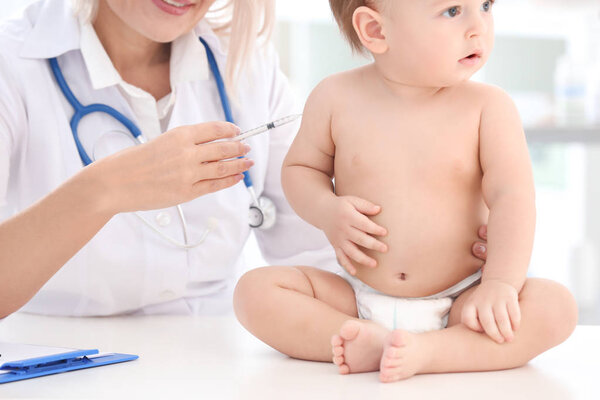 Female doctor vaccinating baby boy in clinic