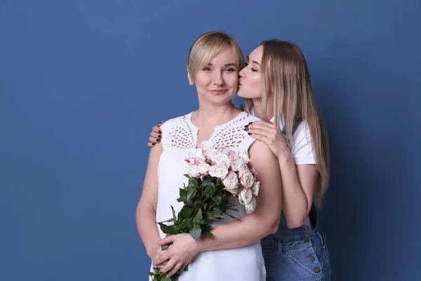 Ung Kvinna Och Hennes Mor Med Bukett Blommor Färgbakgrund — Stockfoto