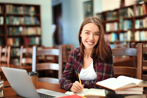 Pretty student with book studying in library