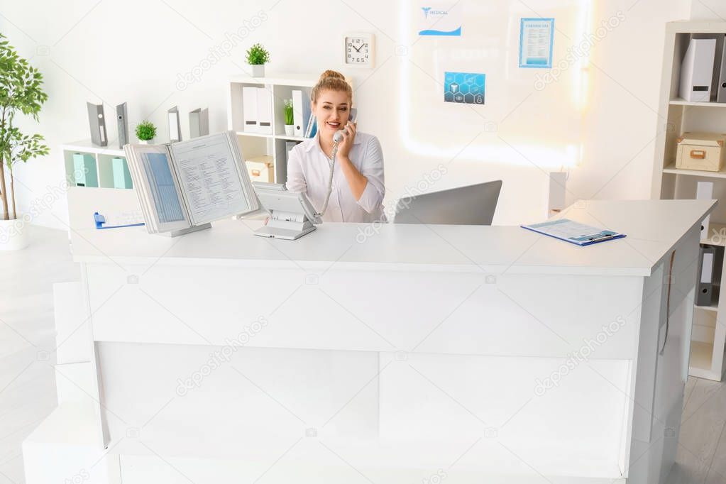 Young trainee passing phone to receptionist in hospital