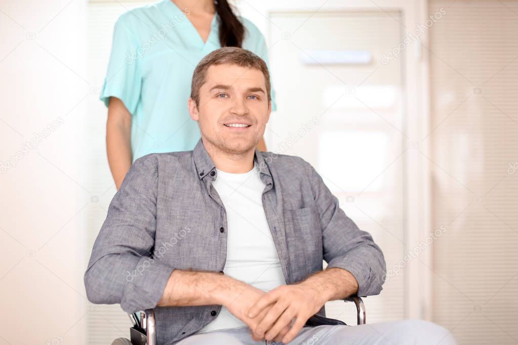 Young female doctor taking care of man in wheelchair indoors