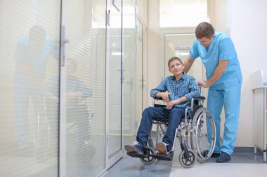 Erkek doktor kapalı tekerlekli sandalyede küçük çocuk bakımı