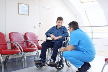 Erkek doktor kapalı tekerlekli sandalyede küçük çocuk bakımı