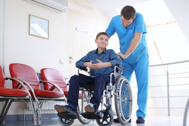 Erkek doktor kapalı tekerlekli sandalyede küçük çocuk bakımı