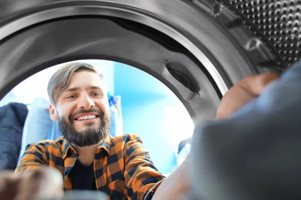 Hombre haciendo la colada en la lavandería, vista desde el interior de la lavadora — Foto de Stock