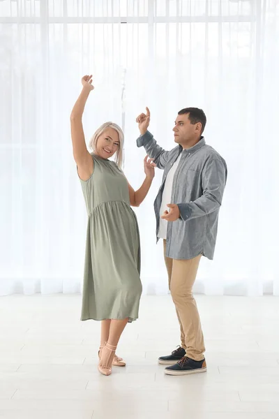 Adorable pareja madura bailando juntos en el interior contra la ventana — Foto de Stock