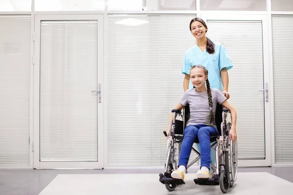 室内での車椅子の少女の世話をする若い女性医師 — ストック写真