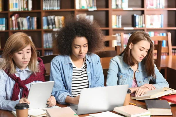 Grupo de estudiantes que estudian en la mesa de la biblioteca — Foto de Stock