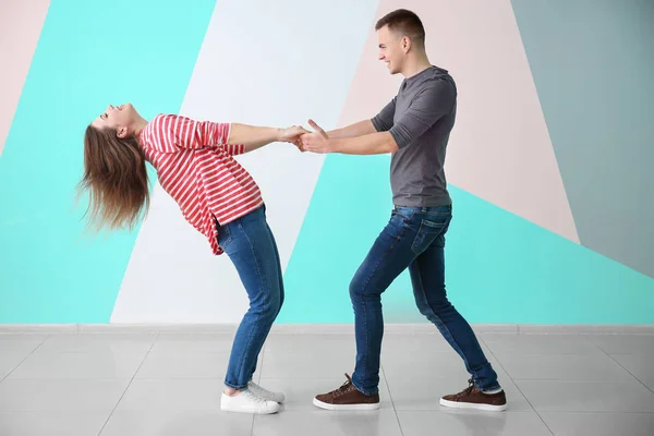Молодая пара танцует вместе у цветной стены — стоковое фото