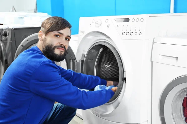 Mand gør vasketøj i vaskeri Stock-billede