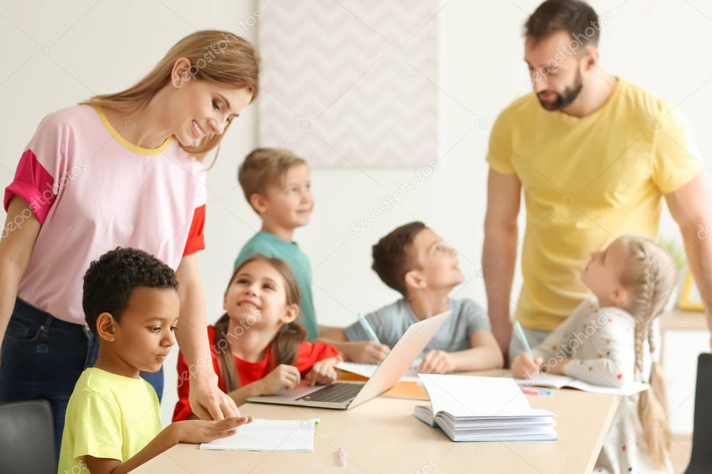 Teachers helping children with homework in classroom at school