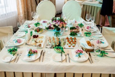 Güzel düğün yemek masası, seçici odak üzerinde cam vazoda krem ve pembe gül buketi. Bir lüks düğün tablo ayarı. Masaya çiçek