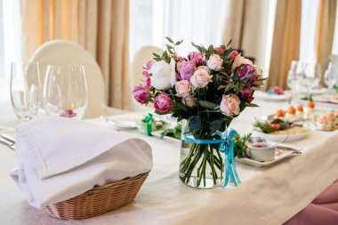 Güzel düğün yemek masası, seçici odak üzerinde cam vazoda krem ve pembe gül buketi. Bir lüks düğün tablo ayarı. Masaya çiçek