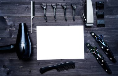 Kuaför araçlar ahşap arka plan üzerinde. Kuaför araçlarıyla düz boş kartı yatıyordu. Üstten görünüm makas, tarak, kesme makinesi ve kurutma makinesi ile boş beyaz kağıt, boş alan ahşap tablo