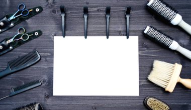 Kuaför araçlar ahşap arka plan üzerinde. Kuaför araçlarıyla düz boş kartı yatıyordu. Makas, tarak, fırçaları ve boş beyaz kağıt, boş alan ile toka ile ahşap masa üzerinde üstten görünüm