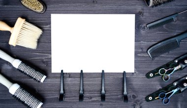 Kuaför araçlar ahşap arka plan üzerinde. Kuaför araçlarıyla düz boş kartı yatıyordu. Makas, tarak, fırçaları ve boş beyaz kağıt, boş alan ile toka ile ahşap masa üzerinde üstten görünüm