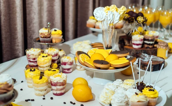 Holiday candy bar in yellow and brown color, selective focus. Wedding candy bar served with lemon biscuits, desserts in glasses, cupcakes, meringues,  lemons and coffee beans