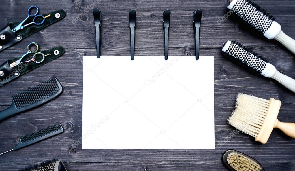Hairdresser tools on wooden background. Blank card with barber tools flat lay. Top view on wooden table with scissors, comb, hairbrushes and hairclips with empty white paper, free space