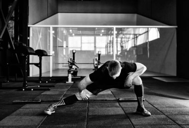 Genç adam eğitim önce kasları hazırlanıyor. Spor salonunda egzersiz kas atlet. Germe adam uygun. Isınma-up profesyonel sporcu. Tam vücut uzunluğu portre