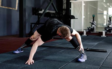 Genç adam eğitim önce kasları hazırlanıyor. Egzersiz kas atlet. Germe adam uygun. Isınma-up profesyonel sporcu