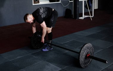 Sakallı adam ağırlık koyarak spor salonunda açık bar. Egzersiz halter ile hazırlanıyor. Vücut geliştirmeci ağırlıkları üzerinde halter koyar.