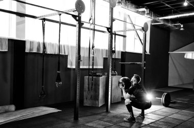 Kaslı adam egzersiz jimnastik salonu sağlık topu ile yapmak. Genç adam ağır ağırlıklı topu ile çalışma dışarı üst vücut egzersiz yaparak