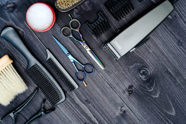 Hairdresser tools on wooden background. Top view on wooden table with scissors, comb, hairbrushes and hairclips, free space. Barbershop, manhood concept