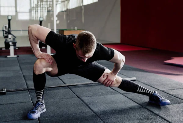 Genç adam eğitim önce kasları hazırlanıyor. Egzersiz kas atlet. Germe adam uygun. Isınma-up profesyonel sporcu