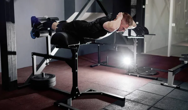 Young man training back muscles. Muscular athlete exercising. Full body length portrait