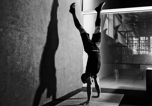 Athlete doing push ups on his hands while standing upside down near red wall. Workout lifestyle concept.  Full body length portrait