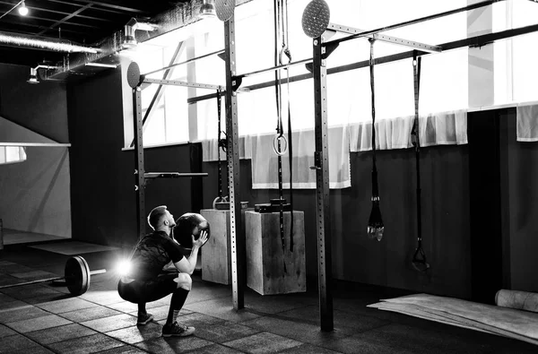 Kaslı adam egzersiz jimnastik salonu sağlık topu ile yapmak. Genç adam ağır ağırlıklı topu ile çalışma dışarı üst vücut egzersiz yaparak