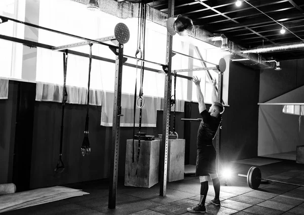 Kaslı adam egzersiz jimnastik salonu sağlık topu ile yapmak. Genç adam ağır ağırlıklı topu ile çalışma dışarı üst vücut egzersiz yaparak