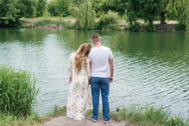 Yürüyüş aşık çift ve nehir kıyısında açık havada sarılma, arkadan görünüm. Boş alan