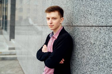 Casual yakışıklı genç ekose gömlek ve ceket taş duvar açık havada, poz boş alan. Genç çapraz eller ile. Tam vücut uzunluğu portre, moda ve insanlar kavramı