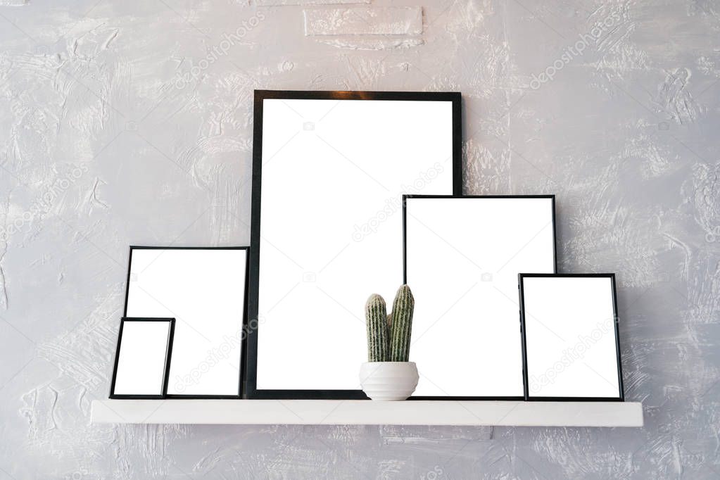 Blank empty white cards with space for text in wooden photo frames. White pot with cactus and photo frames on white shelf on grey background. Blog, website, social media concept, free space