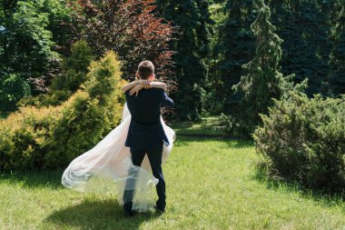 Dans ve having fun güneşli düğün günü genç mutlu evlilik çift. Damat iplik gelin. Elbise rüzgarda geliştirir. Damat holding mutlu duygusal gelin