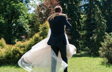 Dans ve having fun güneşli düğün günü genç mutlu evlilik çift. Damat iplik gelin. Elbise rüzgarda geliştirir. Damat holding mutlu duygusal gelin