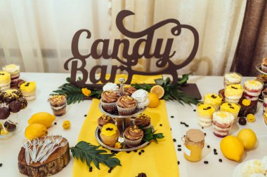 Tatil çikolata kahverengi ve sarı renkte. Çikolata ile cupcakes hizmet düğün, pasta çıkar, gözlük, limon ve kahve çekirdekleri tatlılar 