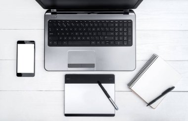 Üstten görünüm ile beyaz tahta masada boş dizüstü bilgisayar, cep telefonu, boş günlüğü ve grafik tablet, boş alan açın. Cep telefonu ile beyaz perde, kopya alanı 