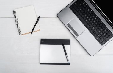 Üstten görünüm açık boş dizüstü bilgisayar, boş günlüğü ve grafik tablet, boş alan beyaz ahşap tablo